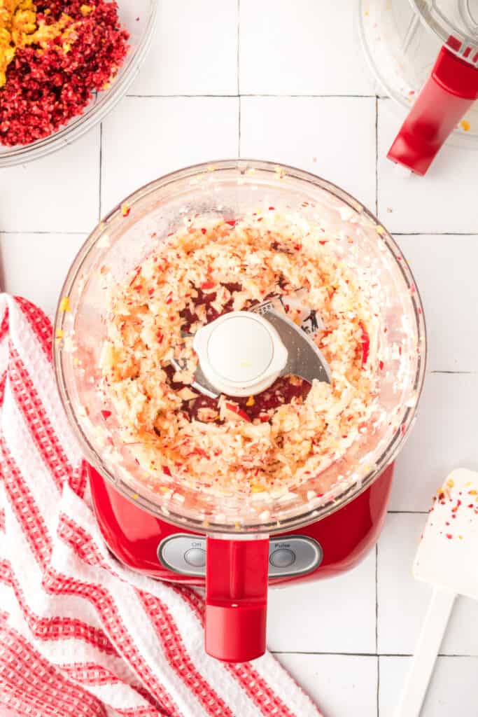 Finely chopped apples inside the red food processor, creating a light, slightly chunky texture.