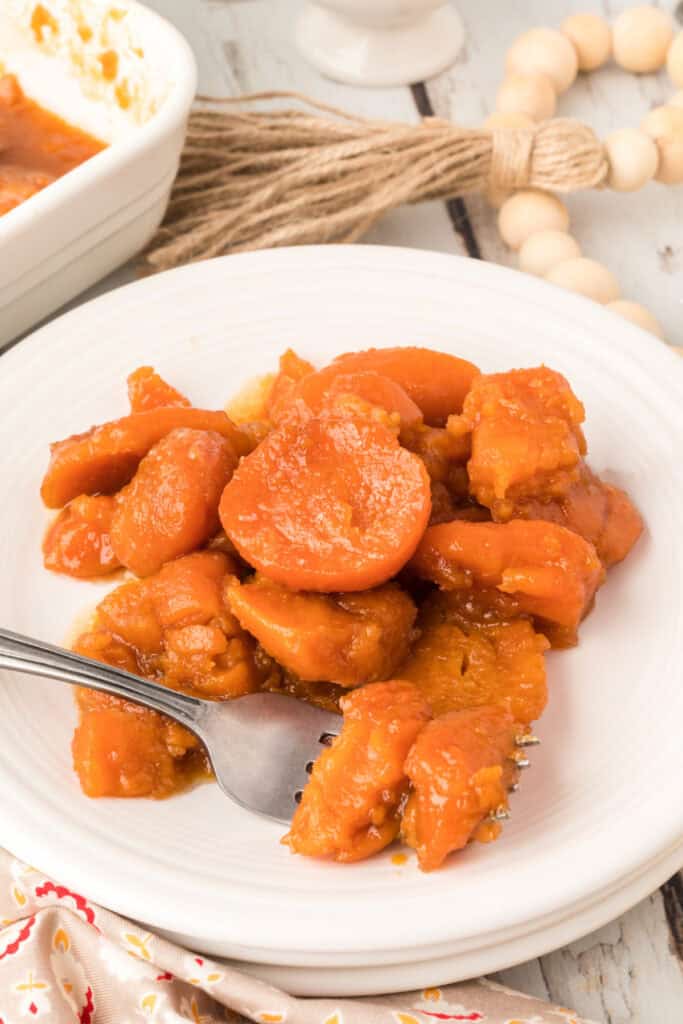 Easy candied yams recipe served on a white plate with tender sweet potatoes coated in brown sugar sauce