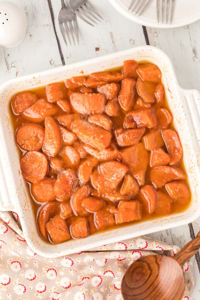 Easy candied yams baked in a white casserole dish with a glossy brown sugar sauce