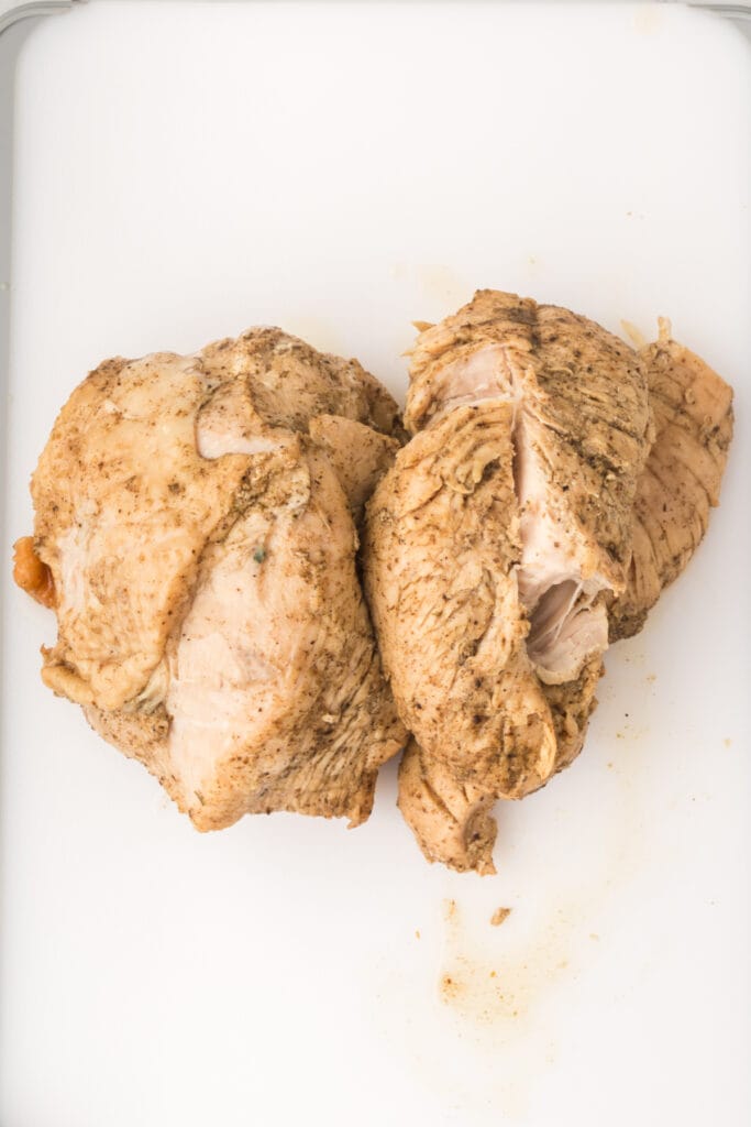 Cooked turkey breast resting on a white cutting board after being removed from the Instant Pot.