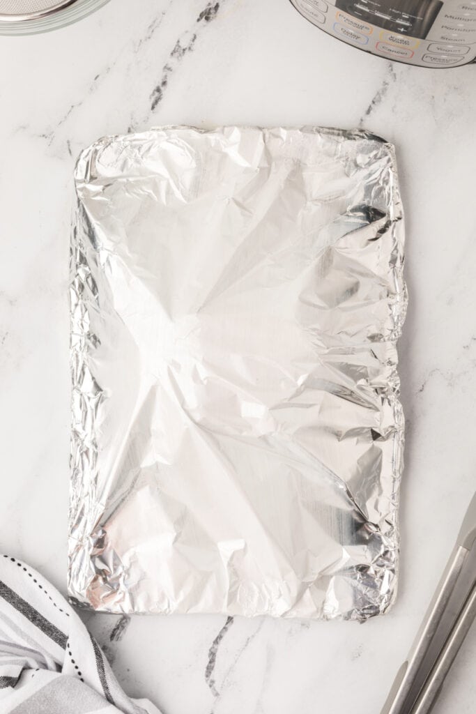 Baking sheet covered with foil, showing the turkey resting under foil to retain moisture.