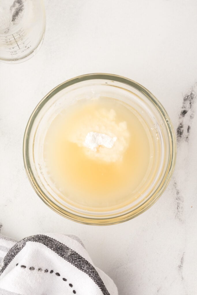 Glass bowl with cornstarch and broth mixture before whisking together to form slurry.