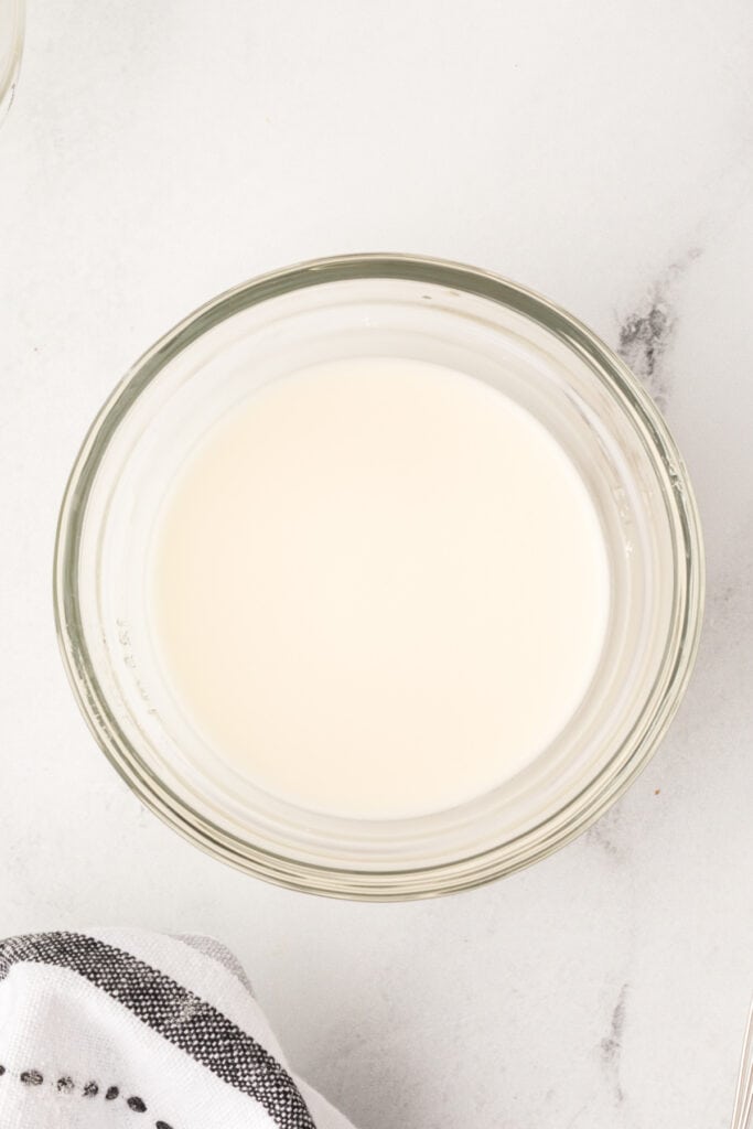 Smooth cornstarch slurry in a glass bowl, ready to be added to drippings for thickening.