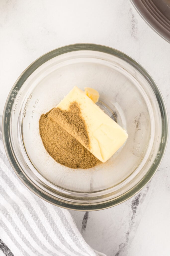 Butter and poultry seasoning in a glass bowl ready to be mixed for turkey seasoning butter.