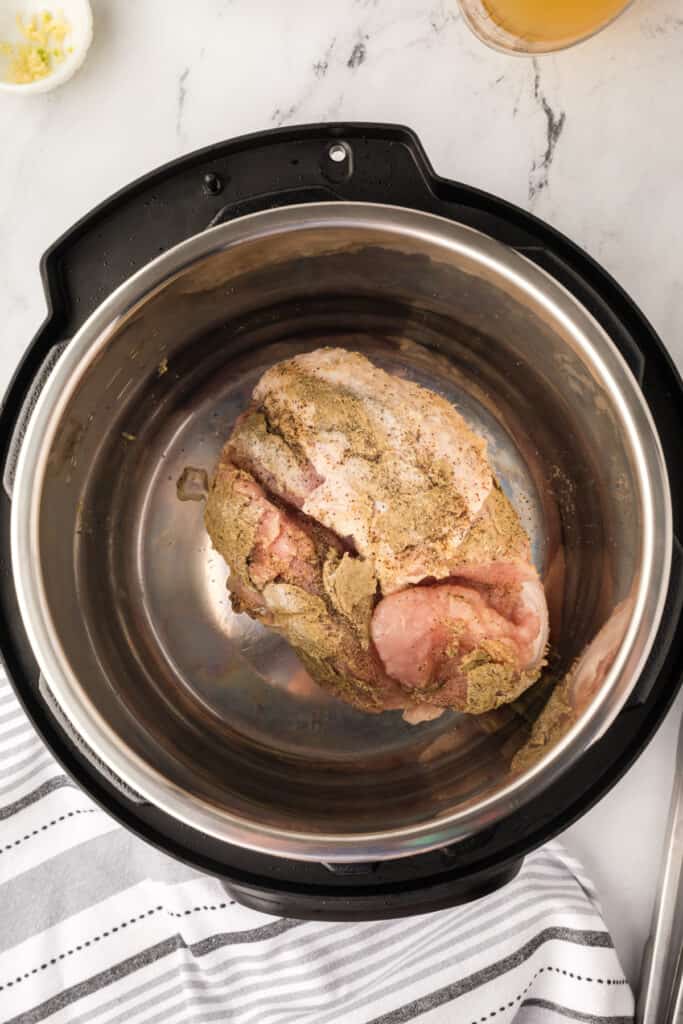 Turkey breast placed inside an Instant Pot inner pot, ready to sear on sauté mode.