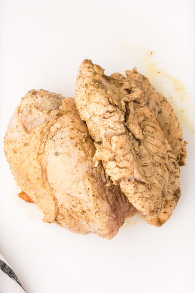 Cooked turkey breast resting on a white cutting board after pressure cooking.