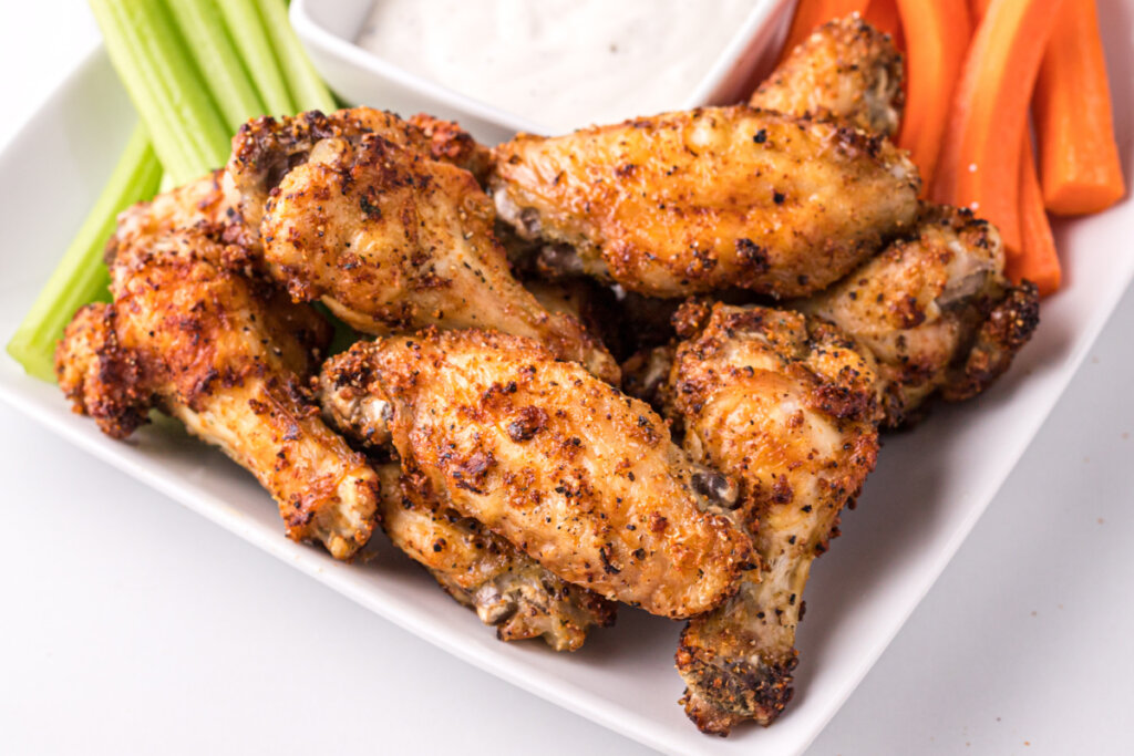 air fryer chicken wings on platter with carrots and celery