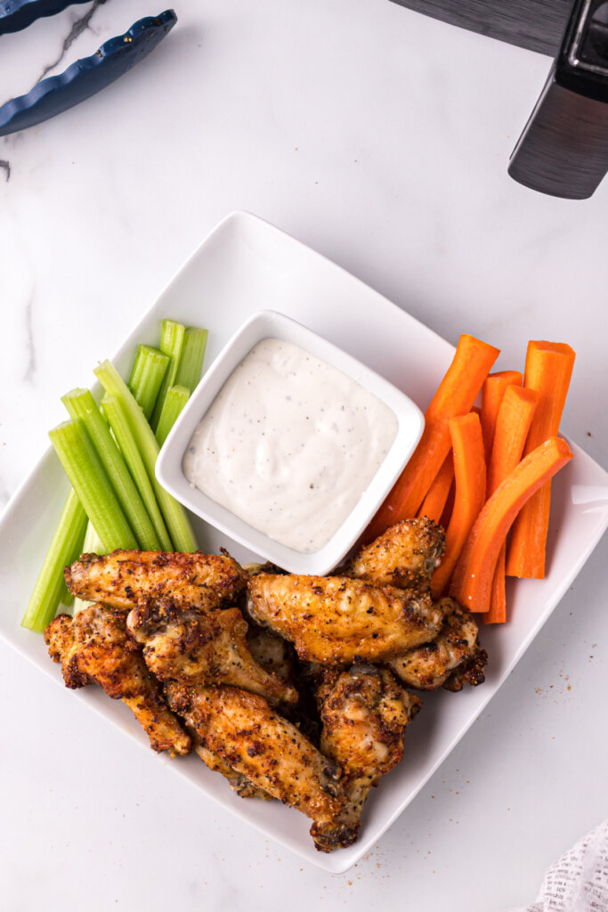looking down onto a platter with air fryer chicken wings, carrots, celery, and dip