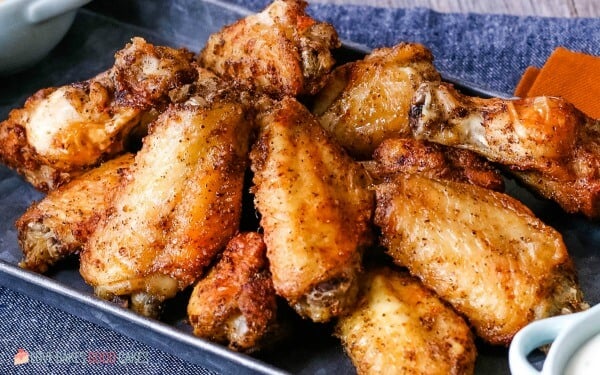 A top down view of the finished air fryer chicken wings on a tray with various dipping sauces. 