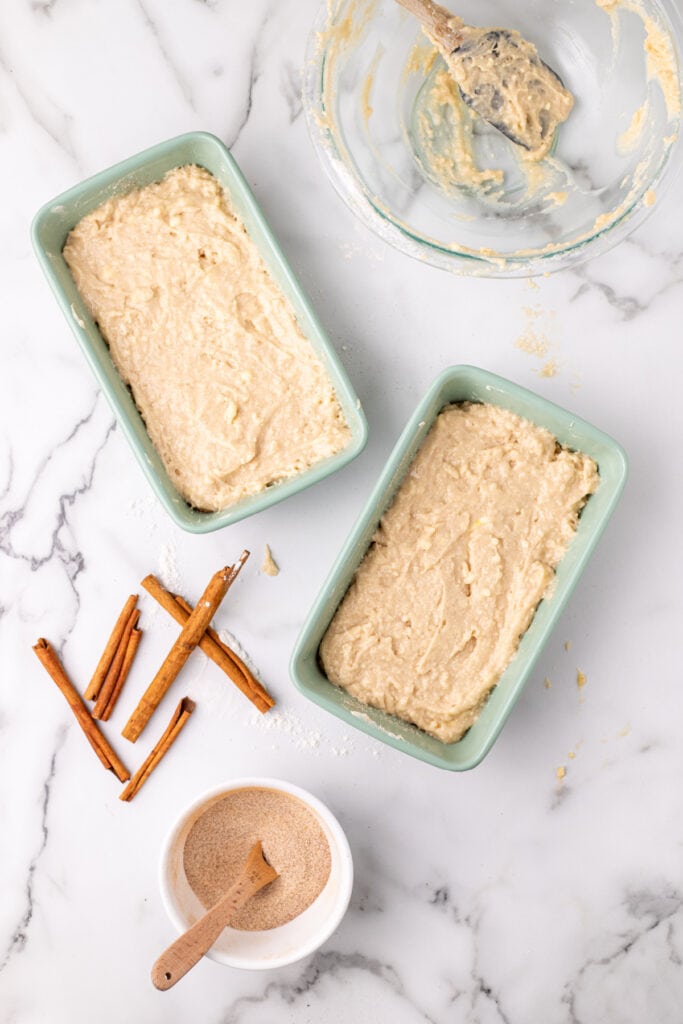 remaining batter spread over the cinnamon-sugar layer in both loaf pans before the final topping