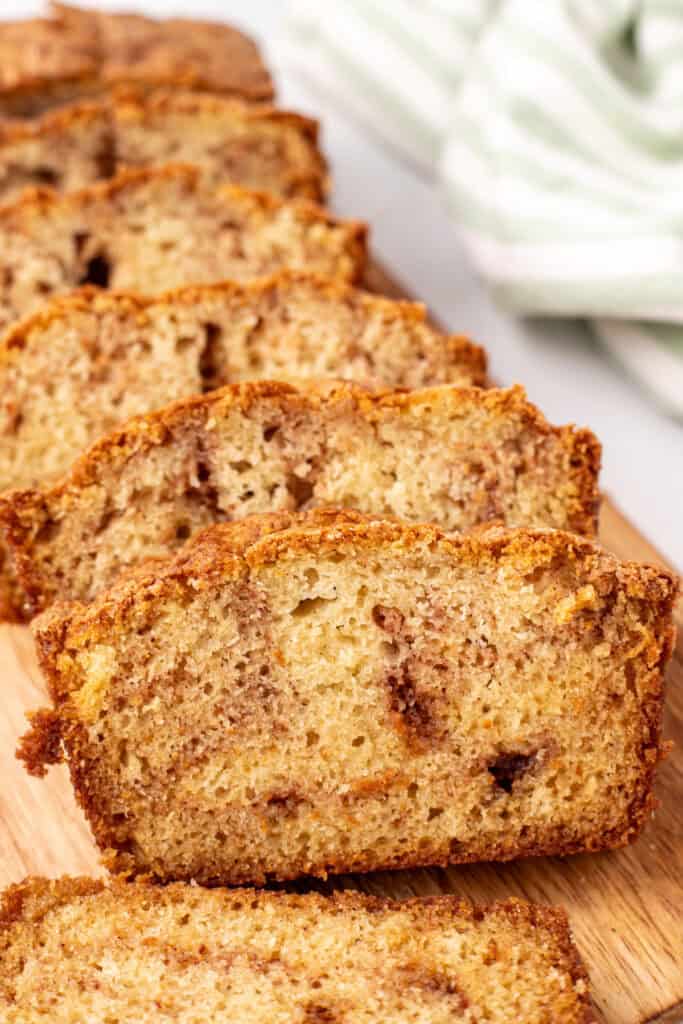 close-up of sliced Amish Cinnamon Bread on a wooden cutting board showing the moist, cinnamon-swirled interior