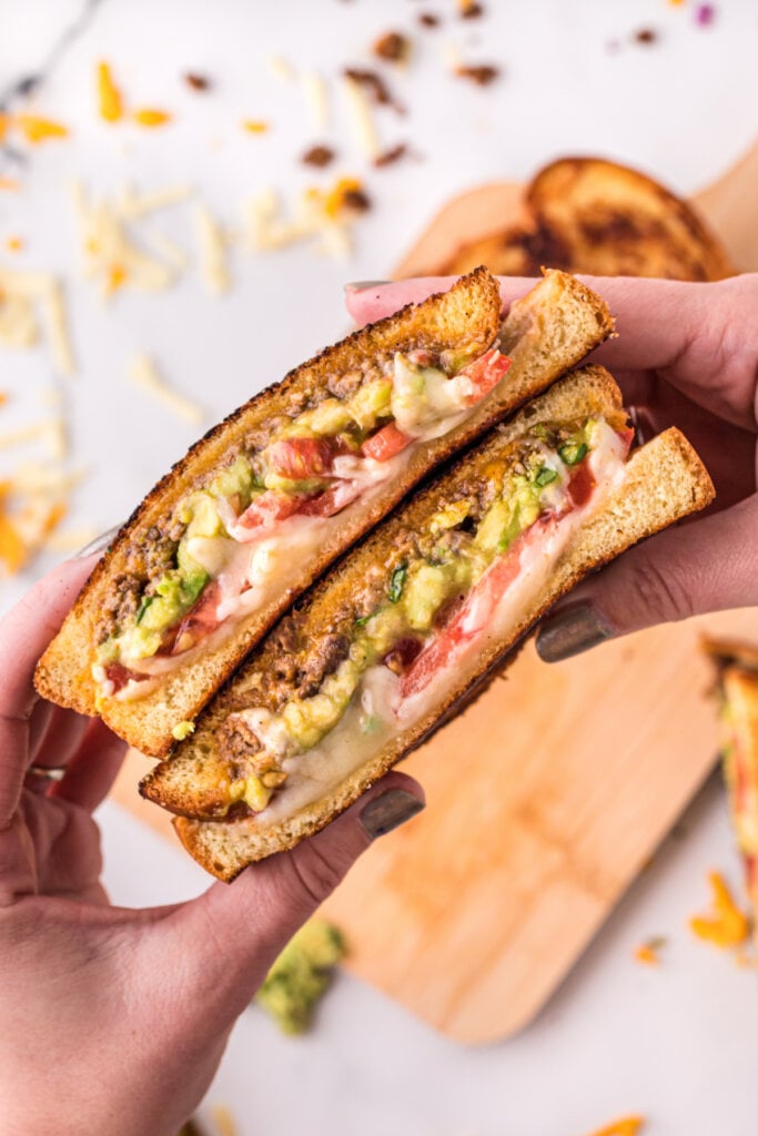 hands holding taco stuffed grilled cheese sandwich