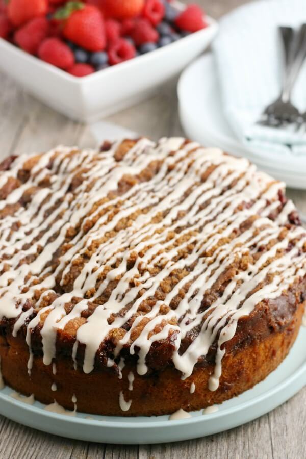 This Blackberry Lemon Coffee Cake is great for brunch, but it could double as a dessert! It's not overly heavy - and the berry and citrus flavor pairs well with the cake. Whole Coffee Cake with Icing, berries and plates inthe background