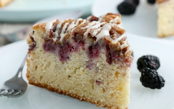 This Blackberry Lemon Coffee Cake is great for brunch, but it could double as a dessert! It's not overly heavy - and the berry and citrus flavor pairs well with the cake. coffee cake on plate with berries and fork