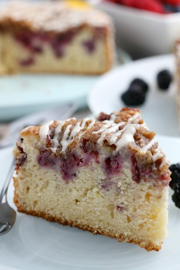 This Blackberry Lemon Coffee Cake is great for brunch, but it could double as a dessert! It's not overly heavy - and the berry and citrus flavor pairs well with the cake. one slice of Blackberry Lemon Coffee Cake on plate