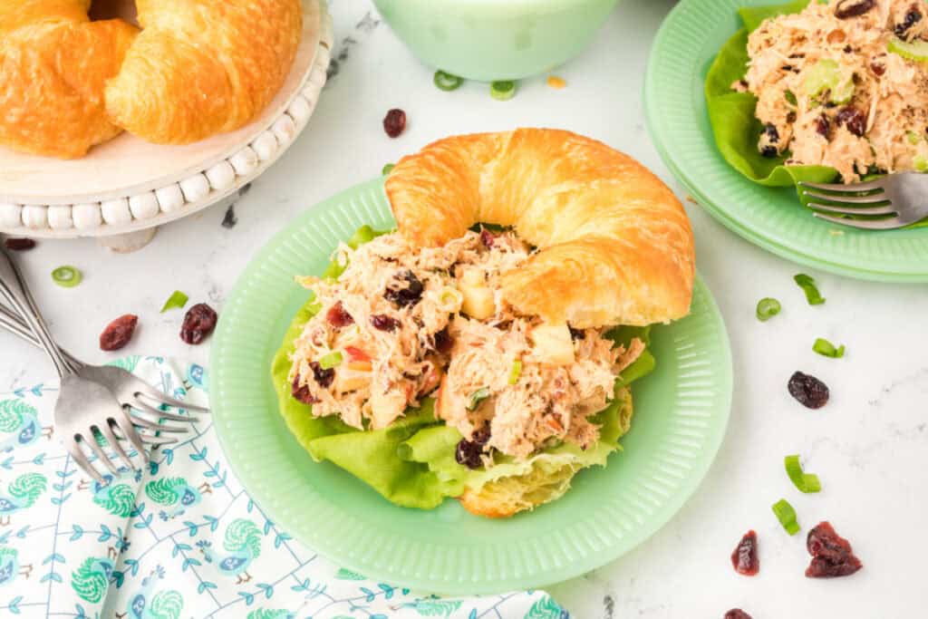 chicken salad with Miracle Whip served on a croissant with lettuce on a green plate