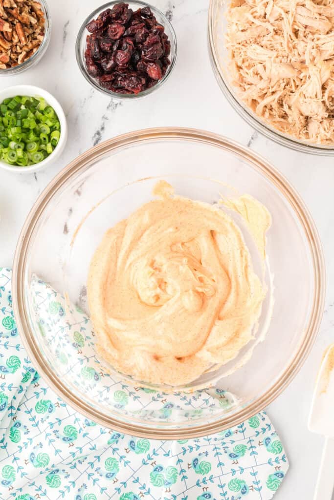 creamy dressing mixture being stirred in a glass bowl for chicken salad with Miracle Whip