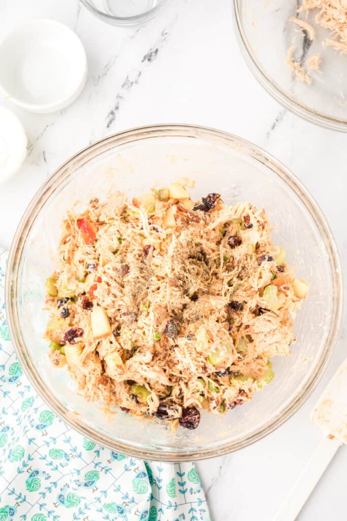 chicken salad with Miracle Whip mixed together in a glass bowl with visible cranberries, celery, and apple pieces