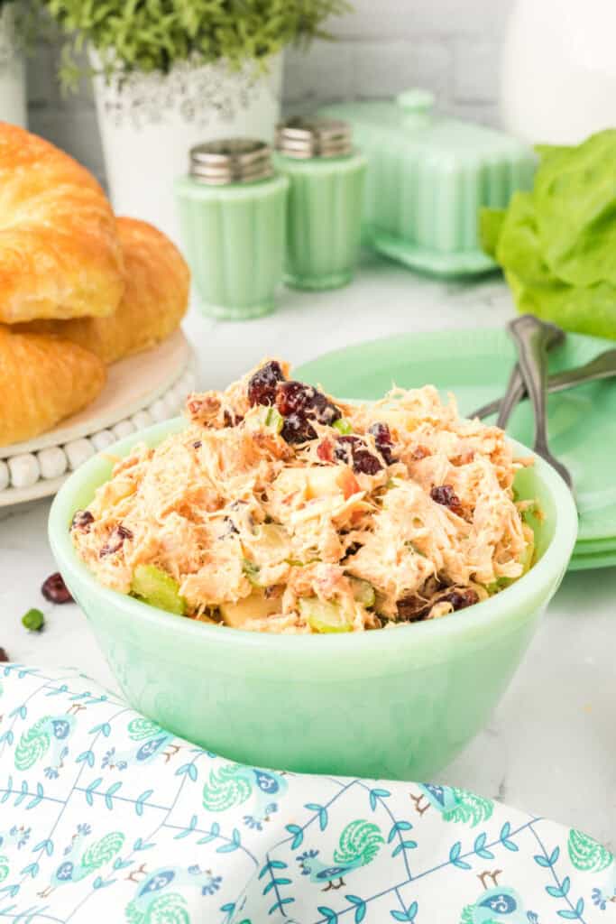 chicken salad with Miracle Whip served in a green bowl with croissants in the background