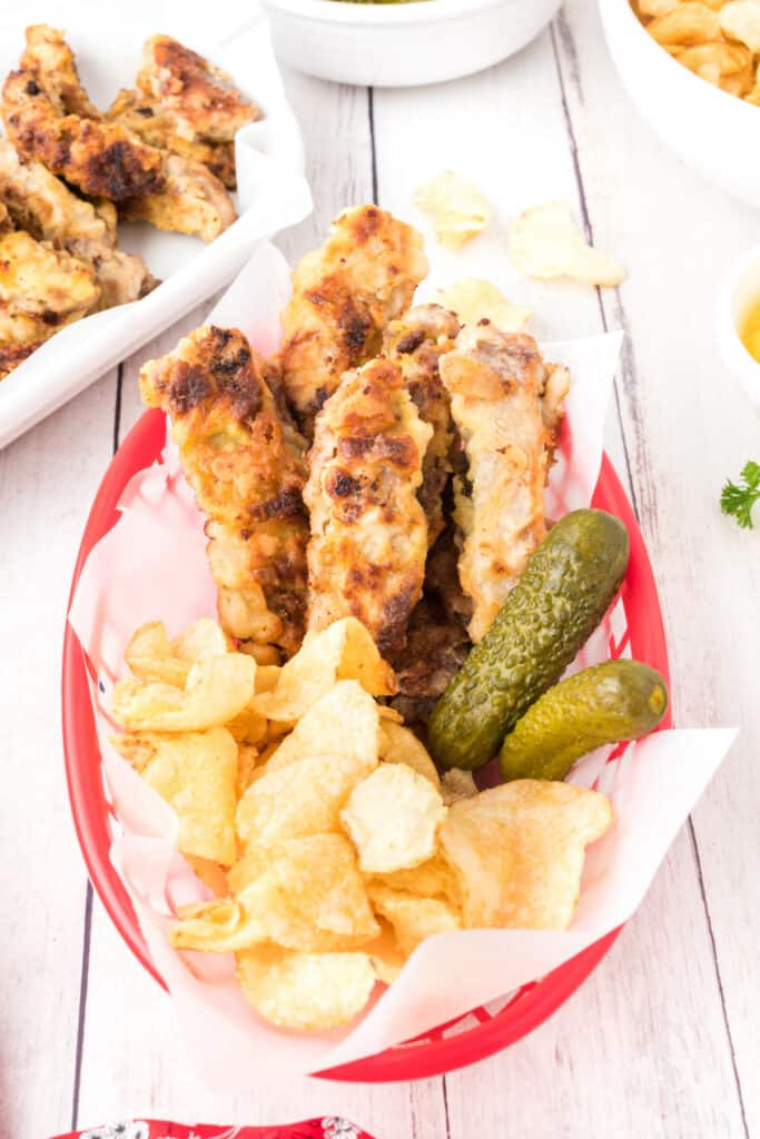 red food basket with steak fingers, potato chips, and pickles