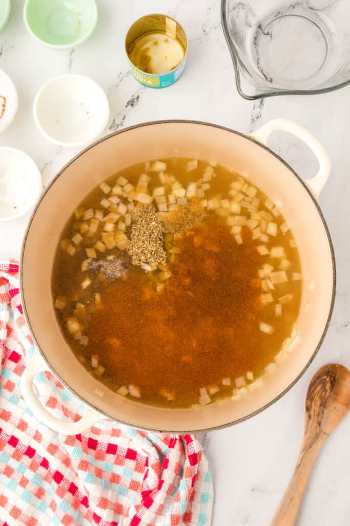 Chicken broth, spices, and green chiles added to sautéed onions in a dutch oven to make the chili base.