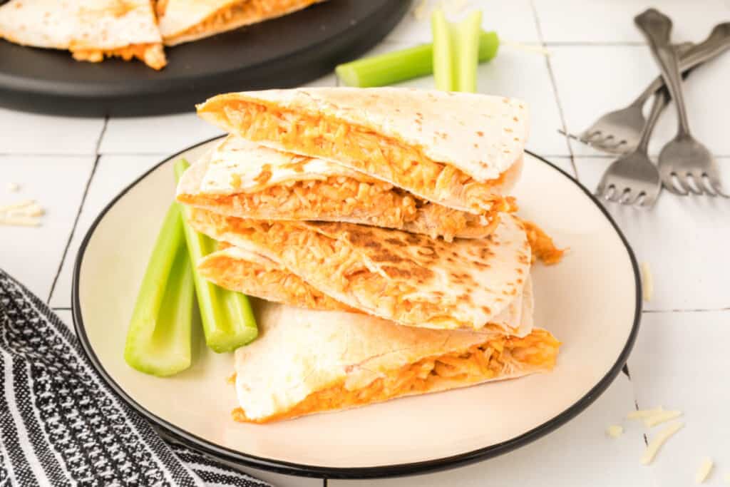 Buffalo Chicken Quesadillas stacked on a plate with celery sticks