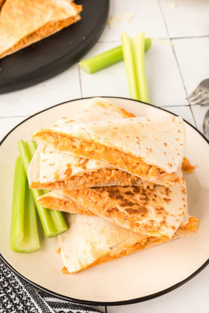 Close-up of Buffalo Chicken Quesadillas with cheesy buffalo chicken filling and celery sticks