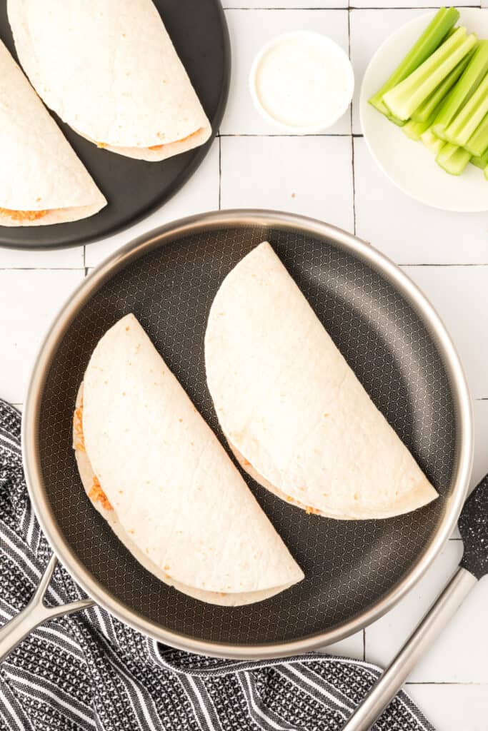 Uncooked Buffalo Chicken Quesadillas in a skillet before crisping