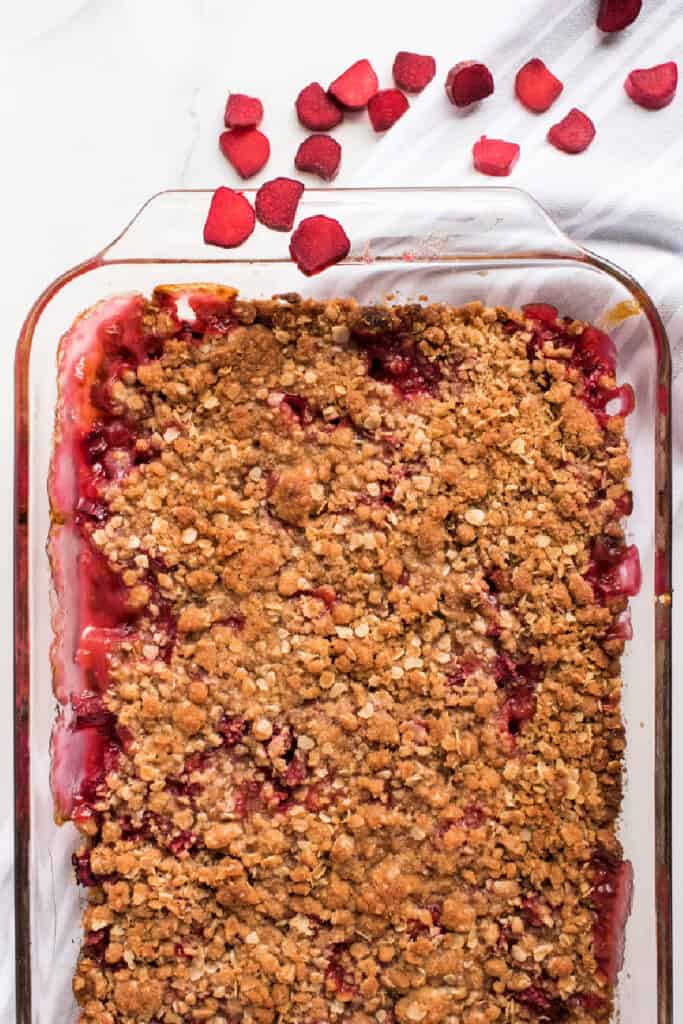 Overhead view of baked rhubarb crisp in a glass baking dish with oat topping and bubbling edges.