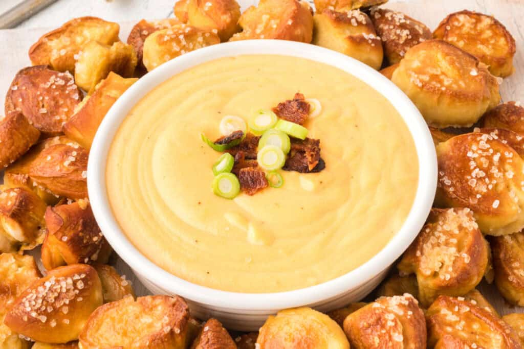 close-up of Beer Cheese Dip in a bowl with pretzel bites around it