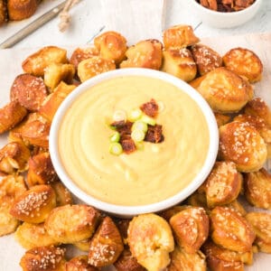 square image of Beer Cheese Dip in a bowl surrounded by pretzel bites
