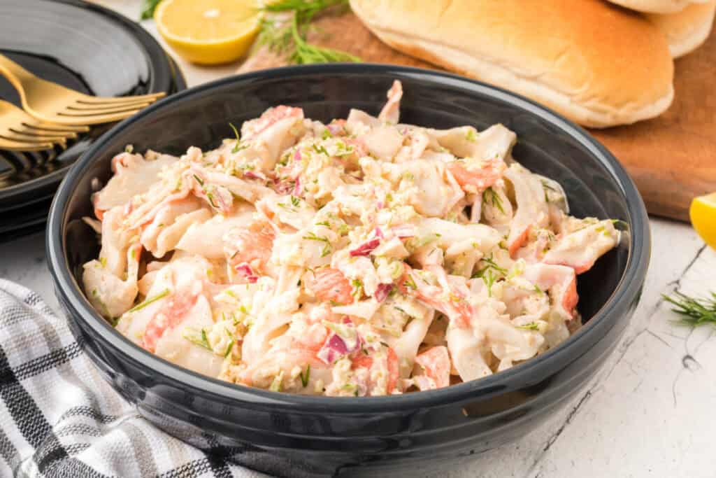 Close-up of creamy Deli-Style Crab Salad with imitation crab, celery, red onion, and fresh dill in a serving bowl.