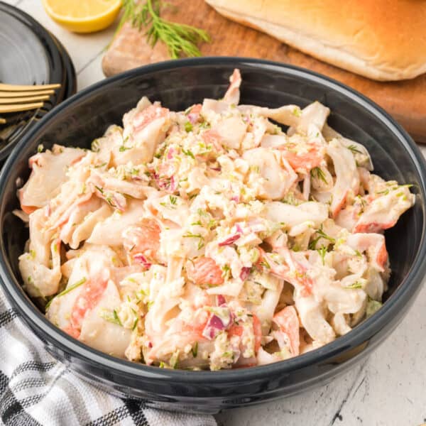 Deli-Style Crab Salad made with imitation crab, celery, red onion, dill, lemon juice, and mayonnaise served in a black bowl.