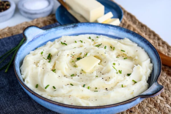 mashed potatoes with a pat of butter and chives in a blue bowl