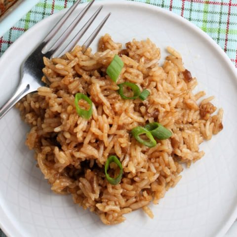 stick of butter rice on white plate garnished with green onions