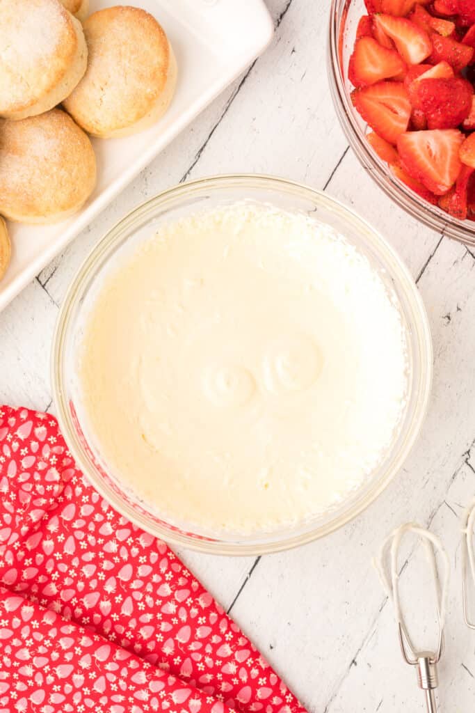 Whipped lemon cream in a glass bowl with strawberries and biscuits nearby.