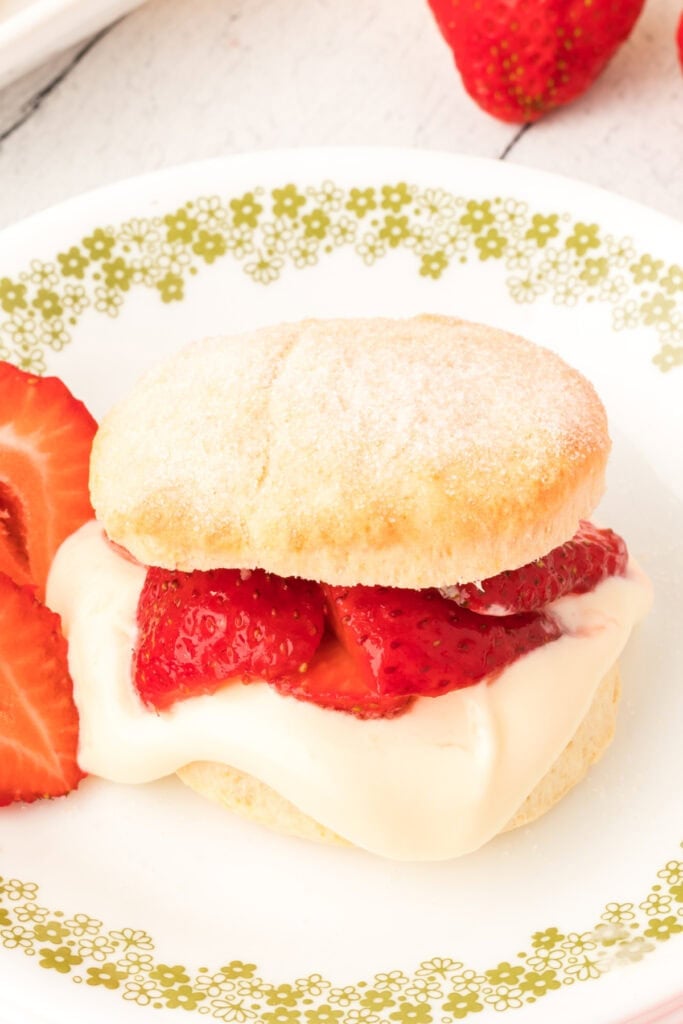 Biscuit filled with lemon cream and strawberries on a plate, with strawberry halves on the side.
