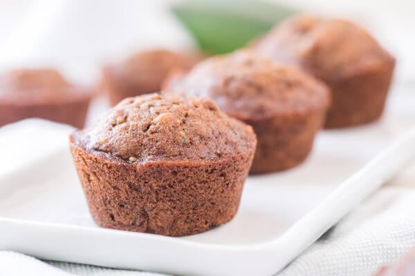 three zucchini muffins lined up on a diagonal on white plate