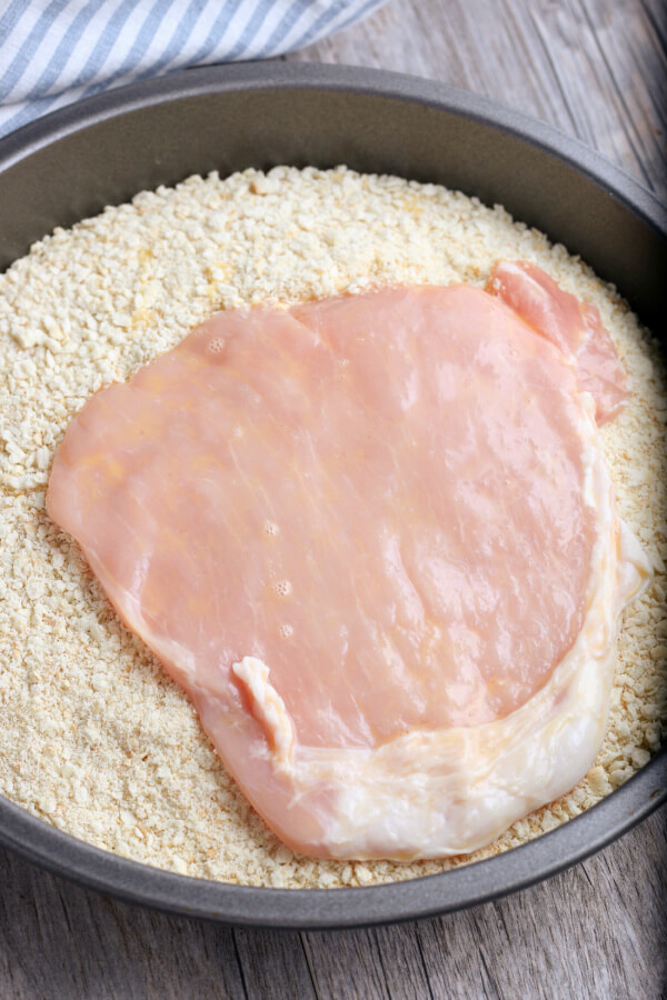 pork tenderloin after egg wash being coated in crack meal