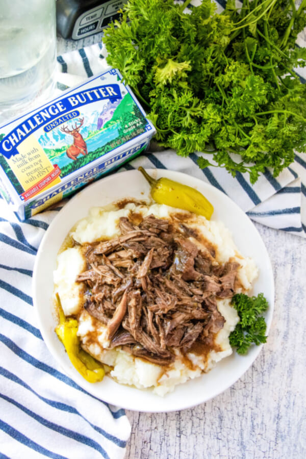 beef in gravy over mashed potatoes. butter and herbs on the side