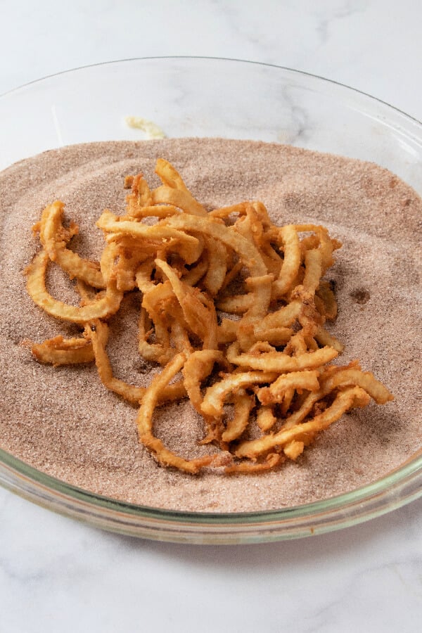 fried apples being coated in cinnamon-sugar mixture