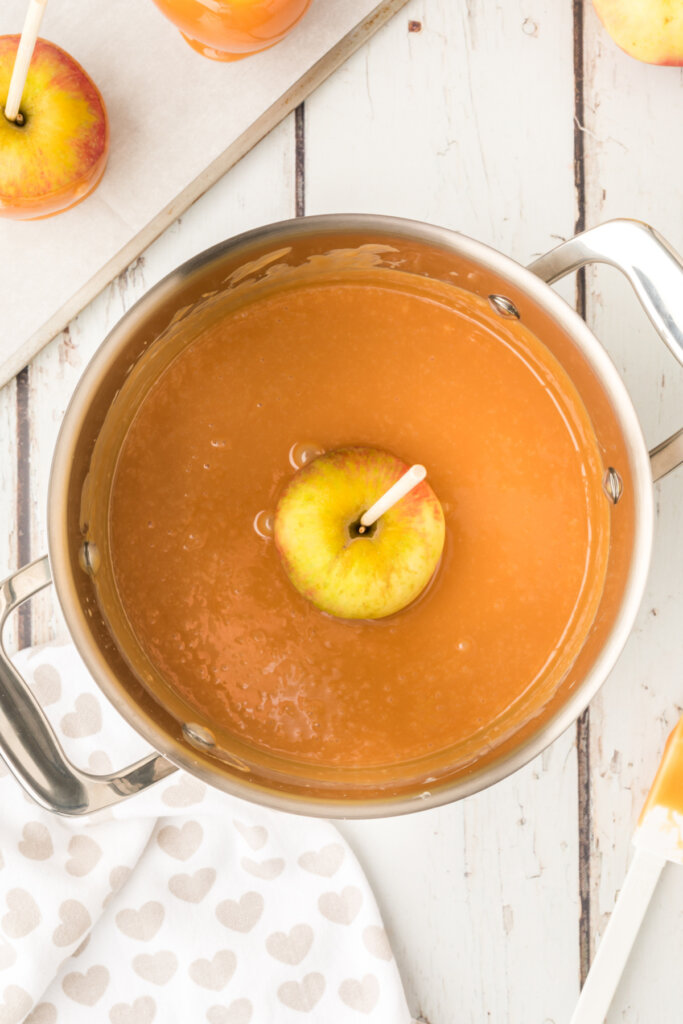 an apple being dipped and coated in caramel