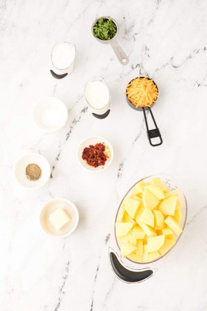 Ingredients for Chipotle Cheddar Mashed Potatoes arranged on a white marble countertop