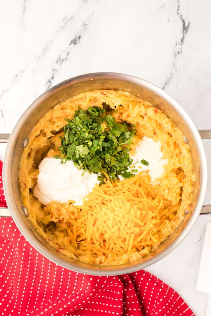 Mashed potatoes topped with sour cream, milk, cilantro, and shredded Cheddar cheese