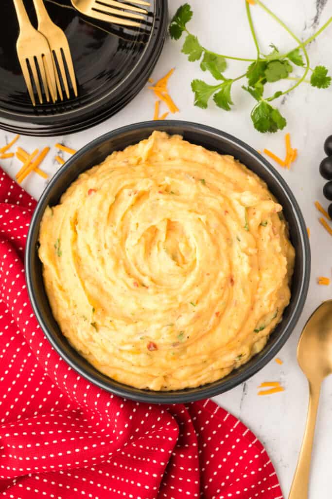 Bowl of Chipotle Cheddar Mashed Potatoes on a white marble countertop