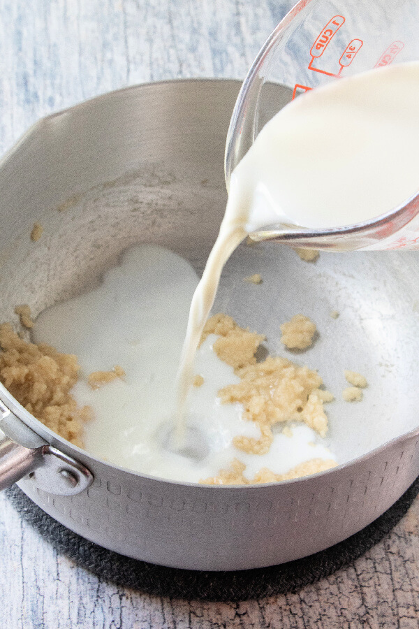 milk being poured into pan with butter and flour mixture