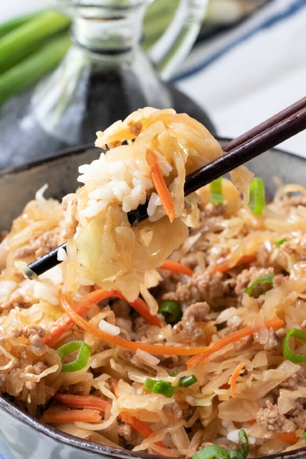 chopsticks holding rice with egg roll in a bowl