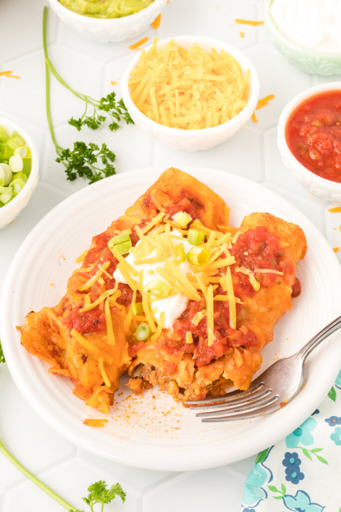 a white plate with two ground beef enchiladas