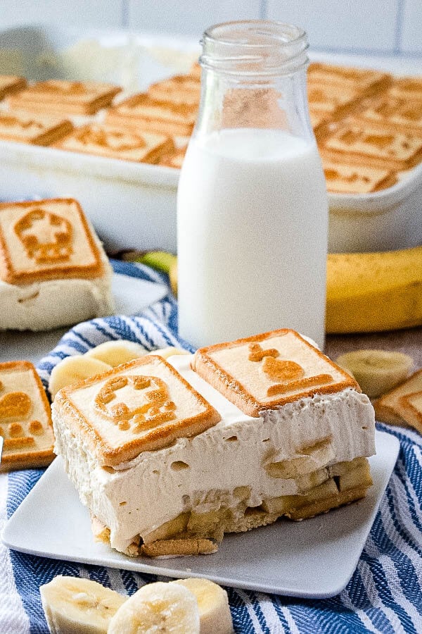 banana pudding on plate with glass of milk and dessert pan in background