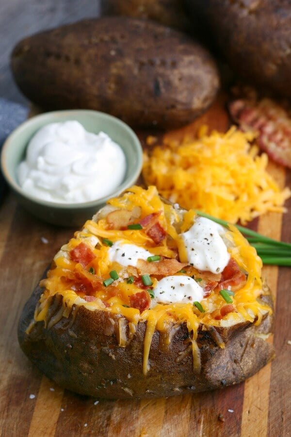 slow cooker baked potato topped with cheese, sour cream, bacon, and chives